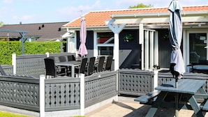 An outdoor patio area with tables and chairs, a covered seating area, and a view of a neighboring building. - Alluring Holiday Home in Hadsund near Sea (Hadsund)