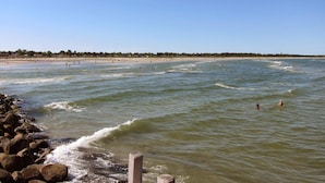 A beach with waves, a rocky shoreline, and a clear sky.