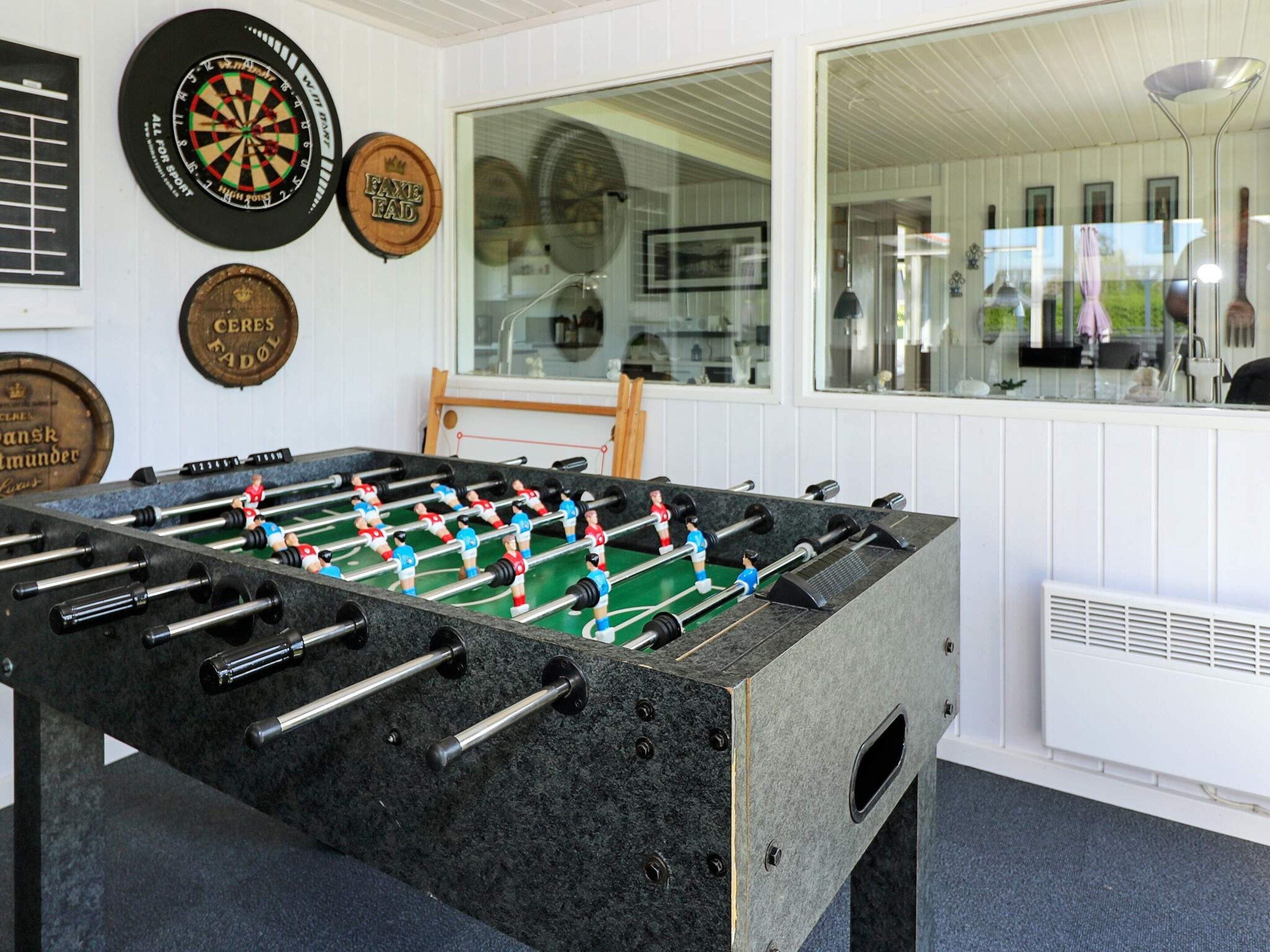 Een tafelvoetbaltafel in een ruimte met dartborden aan de muur.