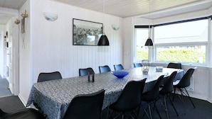A dining area with a table set for six, surrounded by black chairs, a blue bowl, and a black pendant light.