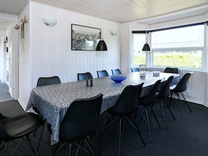 A dining area with a table set for six, surrounded by black chairs, a blue bowl, and a black pendant light. - Alluring Holiday Home in Hadsund near Sea (Hadsund)