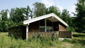 Eine kleine Holzhütte mit Veranda und umzäunter Hof.