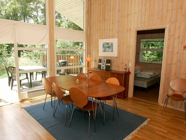 A wooden interior with a dining area, a kitchen, and a sleeping area.