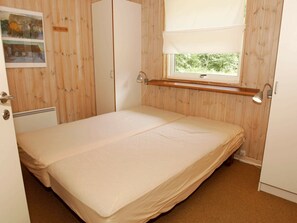 A small, single-bed room with wooden walls, a window with a white blind, and a small shelf above the bed. - Beautiful Holiday Home in Hasle Near Sea (Hasle)