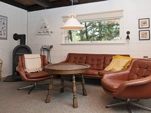 A cozy room with a brown leather sofa, a round wooden table, and a hanging light fixture. - Cozy Holiday Home in Hemmet near Sea (Hemmet)