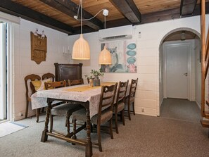 A dining room with a wooden table, chairs, and hanging pendant lights.