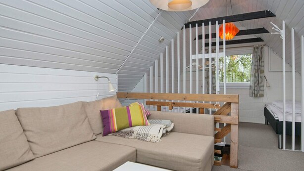 A cozy room with a sofa, a small table, a wooden bench, and a window with curtains. - Cozy Holiday Home in Hemmet near Sea (Hemmet)