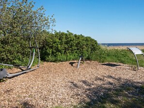 An outdoor area with exercise equipment, a metal sign, and a view of the sea.