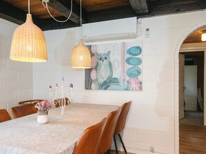 A dining area with a table set for four, a white brick wall, a painting of an owl, and a hanging light fixture. - Cozy Holiday Home in Hemmet near Sea (Hemmet)
