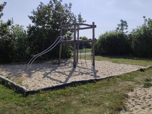 A playground with a wooden climbing structure and a slide.