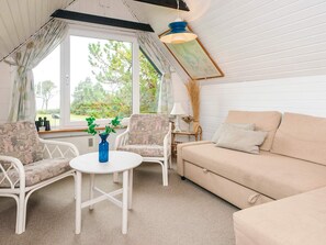 A cozy room with a sofa, two chairs, a small table, and a window with a view of trees. - Cozy Holiday Home in Hemmet near Sea (Hemmet)