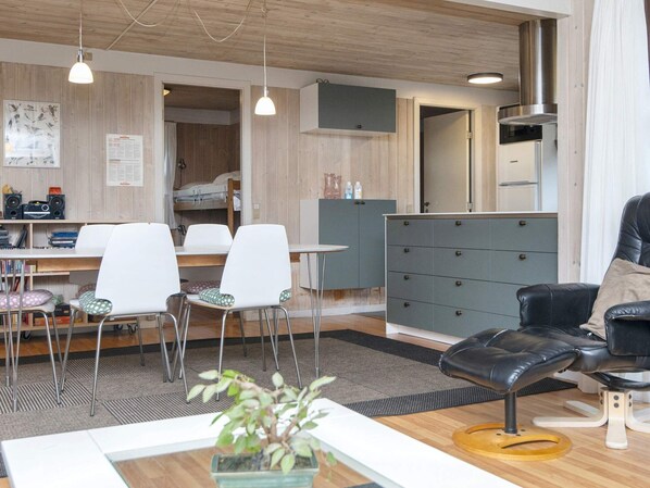 Ein modernes Wohnzimmer mit Essbereich, einem schwarzen Ledersofa und einem grauen Schrank.