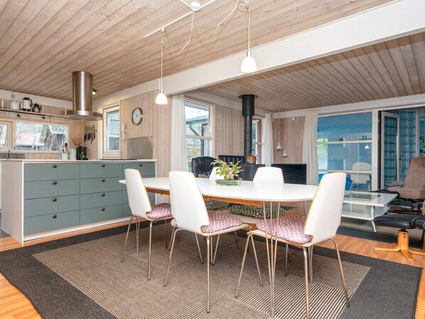 A modern kitchen with a central island, white chairs, and a dining table.