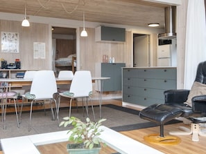 A modern living room with a dining area, a black leather sofa, a wooden dining table, and a grey cabinet. - 5 Star Holiday Home in Glesborg (Glesborg)