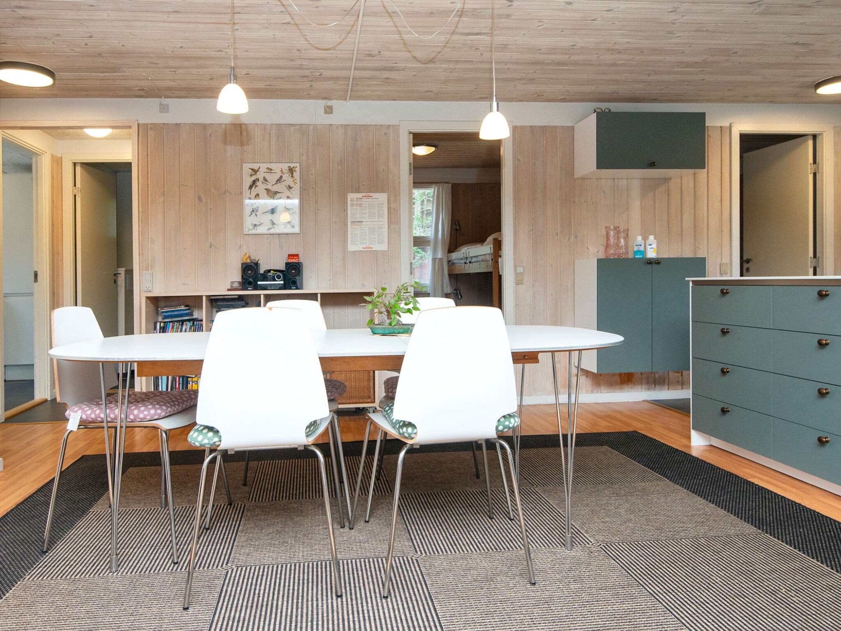 A modern kitchen with a dining table, chairs, and a cabinet.