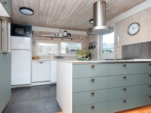 A modern kitchen with a central island, built-in appliances, and a large window providing natural light.