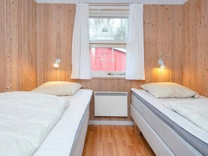 A room with two beds, wooden walls, a window with curtains, and wall-mounted lights. - 5 Star Holiday Home in Glesborg (Glesborg)