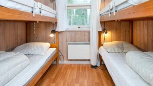 A room with bunk beds, a window with curtains, a heater, and two bedside lamps. - 5 Star Holiday Home in Glesborg (Glesborg)