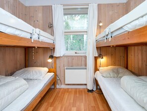 A room with bunk beds, a window with curtains, a heater, and two bedside lamps. - 5 Star Holiday Home in Glesborg (Glesborg)