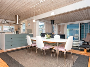A modern kitchen with a central island, white chairs, and a dining table. - 5 Star Holiday Home in Glesborg (Glesborg)