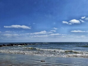 A beach with waves, a clear sky, and a rocky shoreline. - 4 Star Holiday Home in Blavand (Blavand)