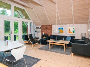 A spacious living area with a high ceiling, a fireplace, a sofa, and a dining table. - 4 Star Holiday Home in Blavand (Blavand)