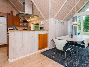 Une cuisine compacte avec des meubles en bois, une cuisinière encastrée et un coin repas comprenant une table ronde et des chaises.