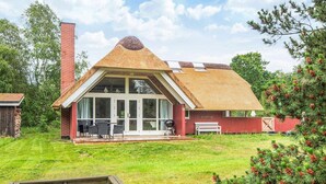 A house with a unique conical roof, large glass windows, and a patio area. - 4 Star Holiday Home in Blavand (Blavand)