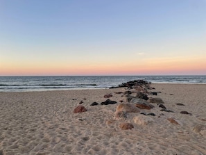 A beach with a row of rocks in the foreground and a calm sea in the background. - 4 Star Holiday Home in Blavand (Blavand)
