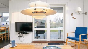 Uma sala de estar moderna com televisão, uma cadeira azul, uma mesa de madeira e uma tigela de vidro.