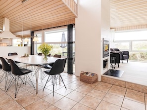 A modern kitchen with a dining area, large windows, and a built-in wood stove. - 5 Star Holiday Home in Hjorring (Hjørring)