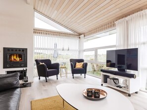 A modern living room with a fireplace, two armchairs, a sofa, a coffee table, and a television. - 5 Star Holiday Home in Hjorring (Hjørring)