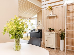 Decoração moderna com área de jantar, mesa redonda e um vaso de flores amarelas.
