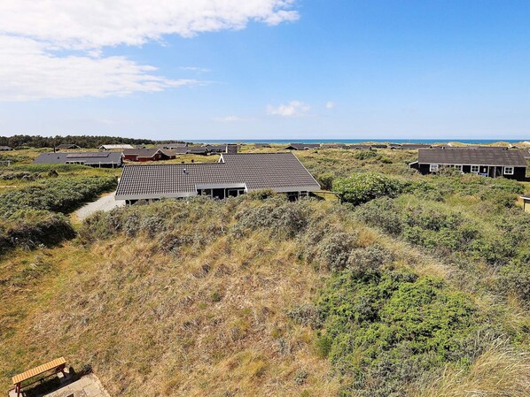 A coastal area with multiple houses, a gravel path, and a bench.