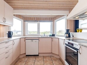 A compact kitchen with a dishwasher, oven, and a window providing natural light.