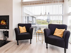 A modern living room with two armchairs, a fireplace, and a large window with a view. - 5 Star Holiday Home in Hjorring (Hjørring)