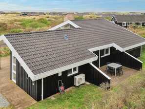 Une maison moderne avec un toit en pente, un patio couvert et un appareil de climatisation.