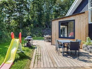 A wooden deck with a table and chairs, a slide, and a barbecue grill.