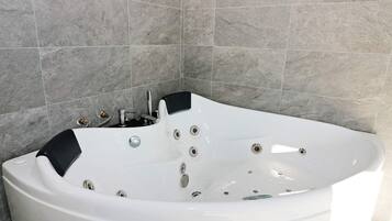 Et moderne badeværelse med et fritstående jacuzzi badekar, et håndholdt brusehoved og en indbygget vandhane.