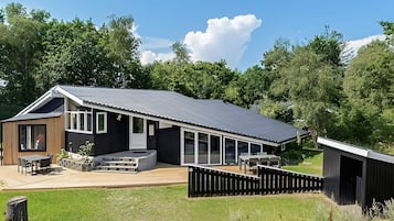 A modern house with a large deck, a covered patio, and a fenced yard.