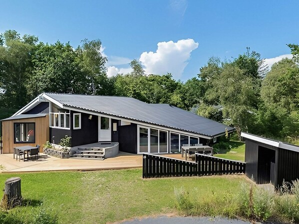 A modern house with a large deck, a covered patio, and a fenced yard.