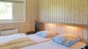 Een kamer met houten wanden, een bed met wit beddengoed, een stoel en een raam.