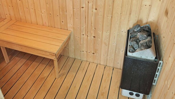 Een houten sauna met een bank en een sauna-oven.
