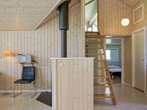 A wooden interior with a loft bed, a ladder, a desk with speakers, and a chair. - 4 Star Holiday Home in Aakirkeby (Akirkeby)