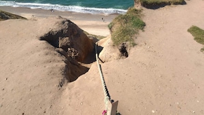 A coastal landscape with a rope barrier, sandy beach, and ocean waves. - 5 Person Holiday Home in Lemvig (Lemvig)