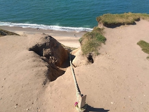 A coastal landscape with a rope barrier, sandy beach, and ocean waves. - 5 Person Holiday Home in Lemvig (Lemvig)