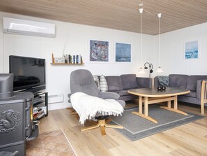 A modern living room with a flat-screen TV, a grey sofa, a wooden coffee table, and a fireplace. - 5 Person Holiday Home in Lemvig (Lemvig)