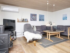 Una sala de estar moderna con un televisor de pantalla plana, un sofá gris, una mesa de centro de madera y una chimenea.