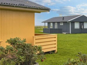 A modern two-story building with a flat roof, a wooden deck, and a well-maintained lawn.
