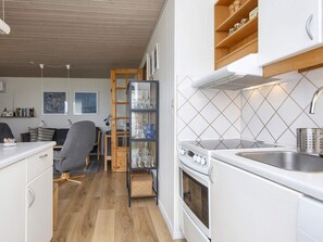 A compact kitchen with a stove, sink, and wooden shelves. - 5 Person Holiday Home in Lemvig (Lemvig)